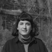 black and white image of Kaitlin Pomerantz, white femme with dark hair and bangs, collared shirt