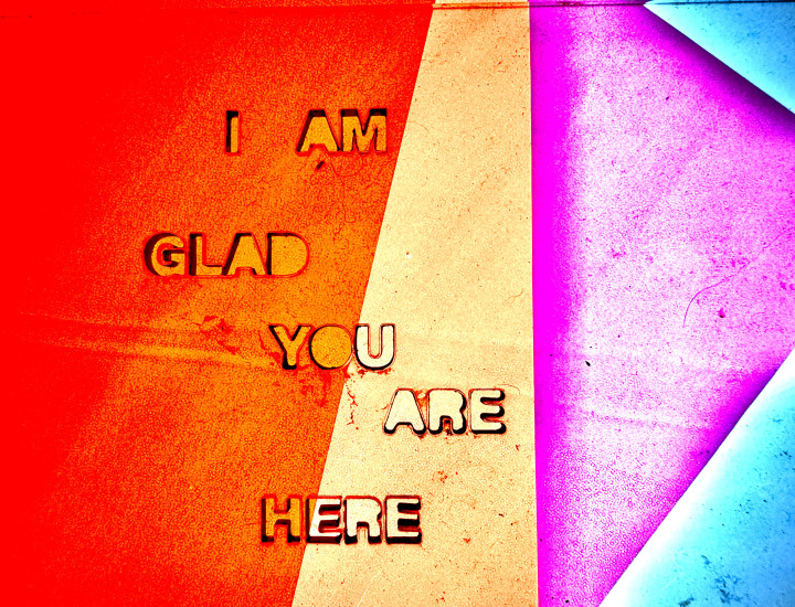 colorful geometric backlit shapes present the text "i am glad you are here" in red, dusty yellow, magenta, and cyan